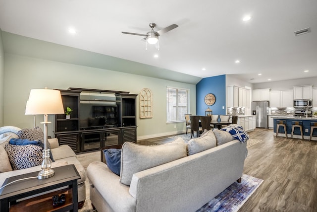 living room with recessed lighting, visible vents, light wood-style flooring, vaulted ceiling, and baseboards