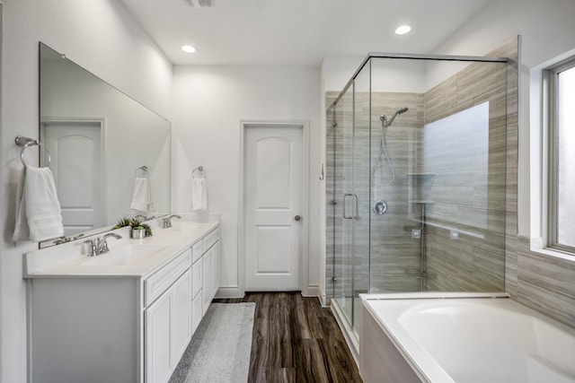 bathroom with double vanity, wood finished floors, a sink, a shower stall, and a bath