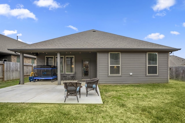 back of property featuring a trampoline, fence, a lawn, and a patio