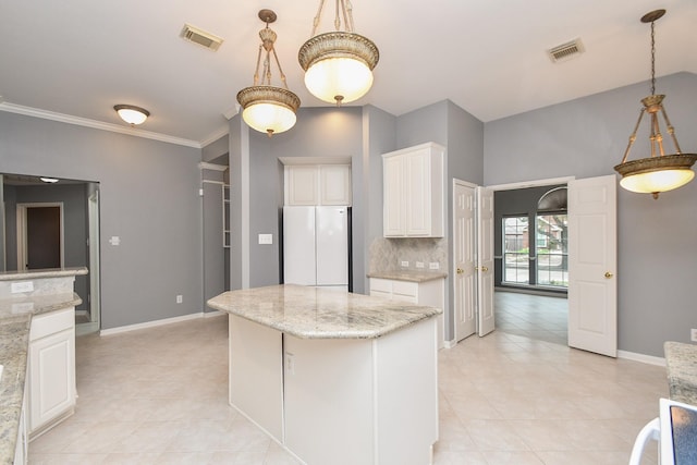 kitchen featuring visible vents, freestanding refrigerator, white cabinetry, a kitchen island, and light stone countertops