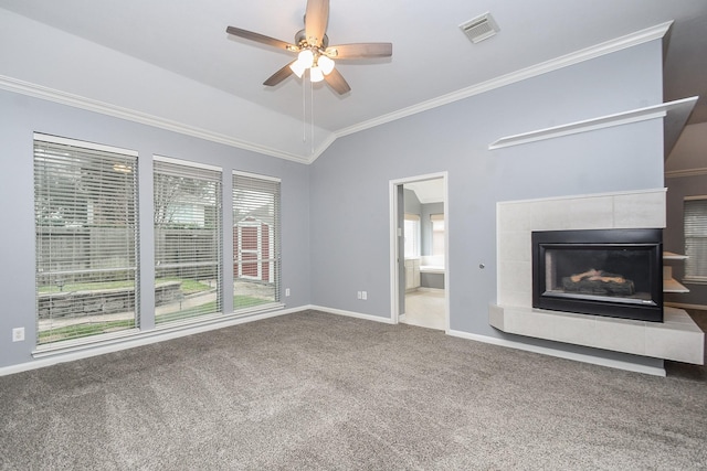 unfurnished living room with lofted ceiling, a tile fireplace, visible vents, carpet, and crown molding