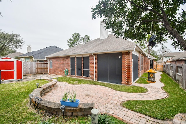 back of property featuring a patio, a fenced backyard, a chimney, a shed, and brick siding