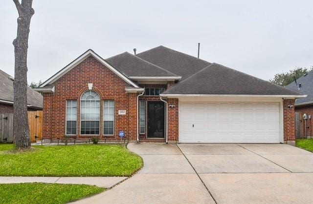 single story home with a garage, brick siding, fence, driveway, and a front lawn