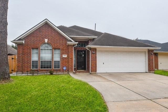 single story home featuring driveway, brick siding, a front lawn, and an attached garage