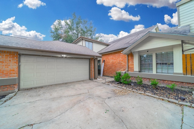 exterior space with driveway, an attached garage, a shingled roof, and brick siding