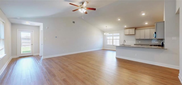 unfurnished living room featuring lofted ceiling, ceiling fan, visible vents, baseboards, and light wood-style floors