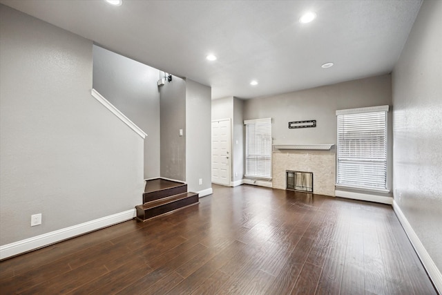 unfurnished living room featuring dark wood-style floors, recessed lighting, a fireplace, and baseboards