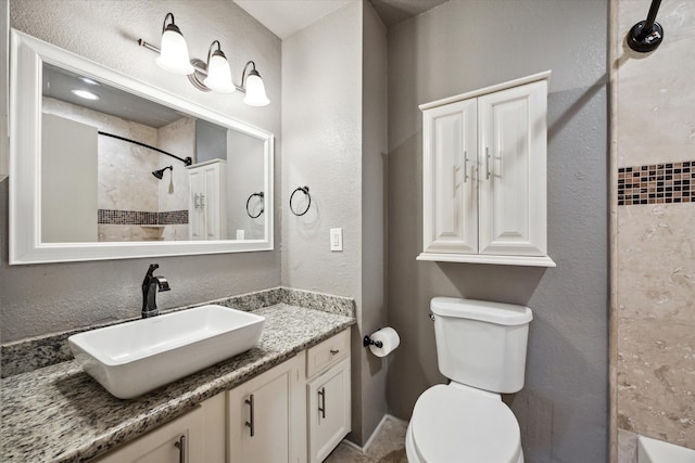 bathroom featuring toilet, a textured wall, and vanity