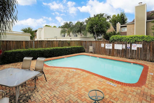 pool with a patio area and fence