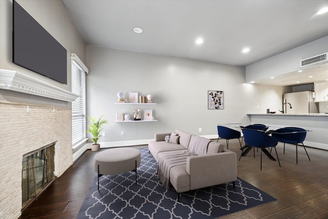 living area featuring dark wood-style floors, a fireplace, visible vents, and baseboards