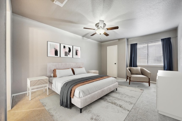 bedroom with light carpet, baseboards, visible vents, and a textured ceiling