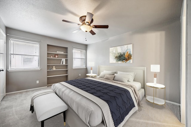 bedroom featuring light carpet, ceiling fan, a textured ceiling, and baseboards