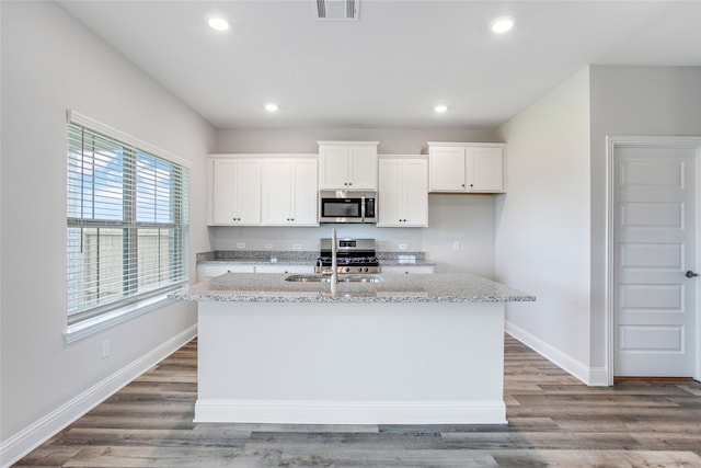 kitchen featuring visible vents, appliances with stainless steel finishes, white cabinetry, and light stone countertops