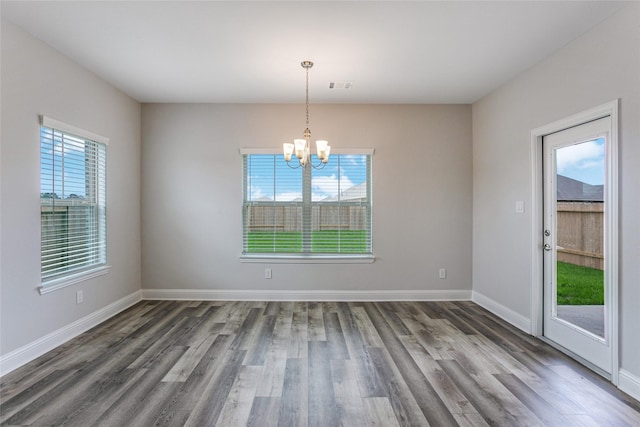 unfurnished room with a chandelier, a wealth of natural light, dark wood-style floors, and visible vents