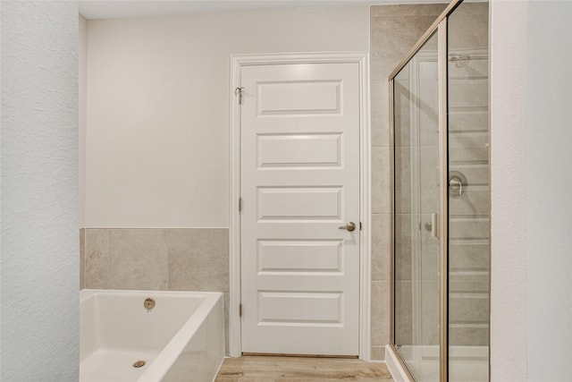 full bath with wood finished floors, a stall shower, and a garden tub