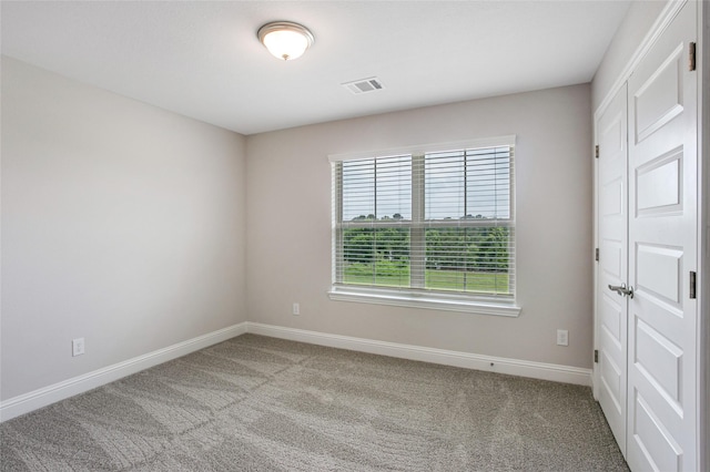 carpeted spare room with visible vents and baseboards