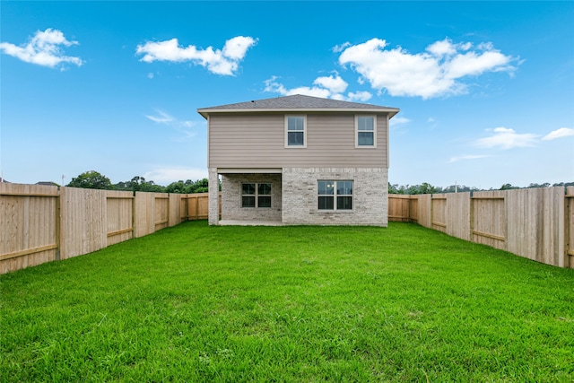 rear view of property featuring a fenced backyard, a lawn, and brick siding