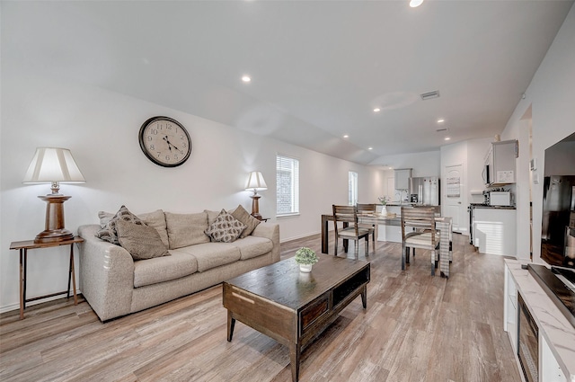 living room with lofted ceiling, light wood-style floors, visible vents, and recessed lighting