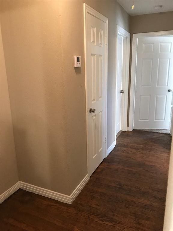 hall with baseboards and dark wood-type flooring