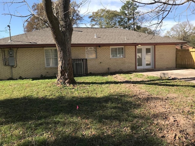 rear view of property featuring french doors, brick siding, a lawn, a patio area, and fence