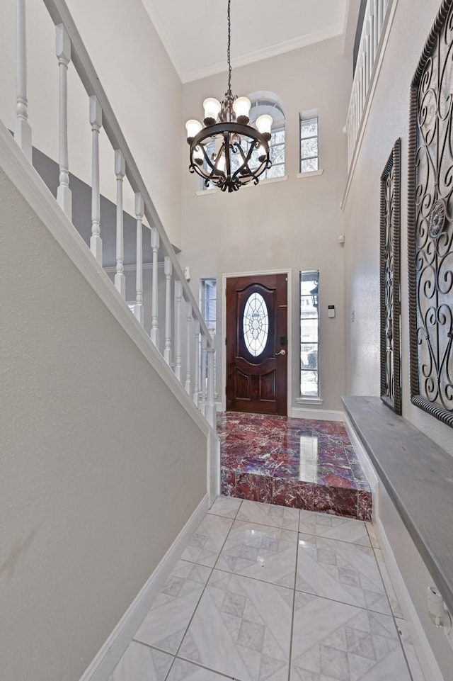 entryway featuring crown molding, baseboards, a chandelier, stairway, and marble finish floor