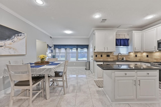 kitchen with dark countertops, visible vents, white cabinets, stainless steel appliances, and a sink