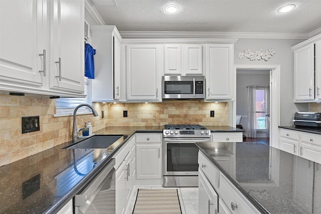 kitchen featuring white cabinets, backsplash, appliances with stainless steel finishes, and a sink