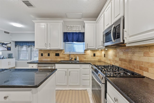 kitchen with decorative backsplash, white cabinets, appliances with stainless steel finishes, and a sink