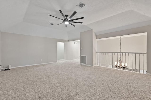 carpeted spare room with vaulted ceiling, ceiling fan with notable chandelier, visible vents, and baseboards