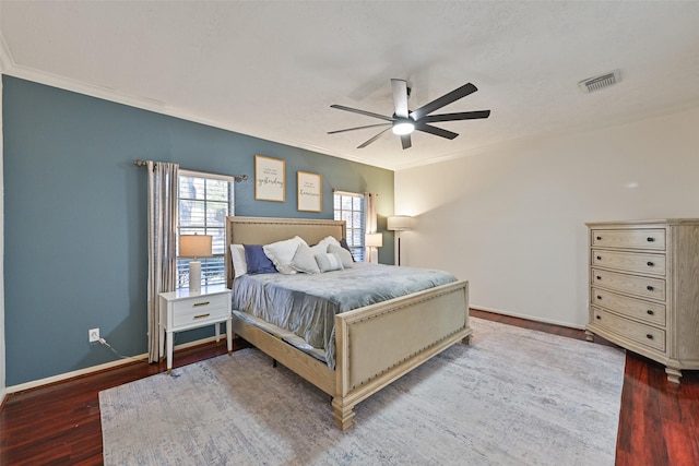 bedroom with visible vents, crown molding, baseboards, and wood finished floors