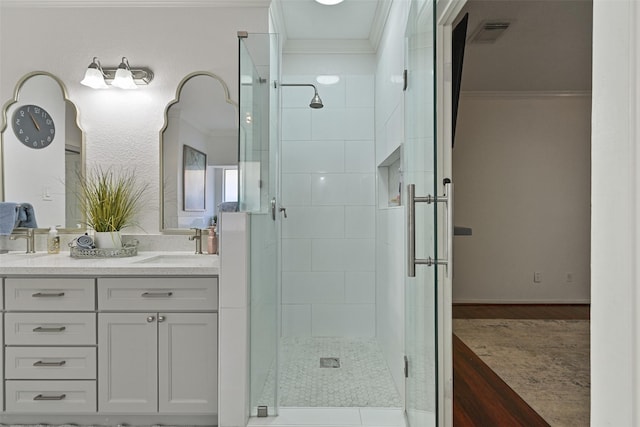 bathroom with visible vents, double vanity, a sink, ornamental molding, and a shower stall