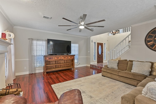 living area featuring visible vents, a textured ceiling, wood finished floors, stairway, and crown molding