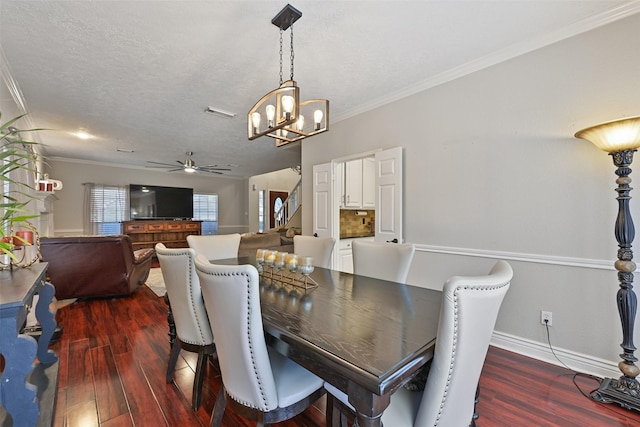 dining room featuring dark wood-type flooring, baseboards, ornamental molding, ceiling fan with notable chandelier, and a textured ceiling