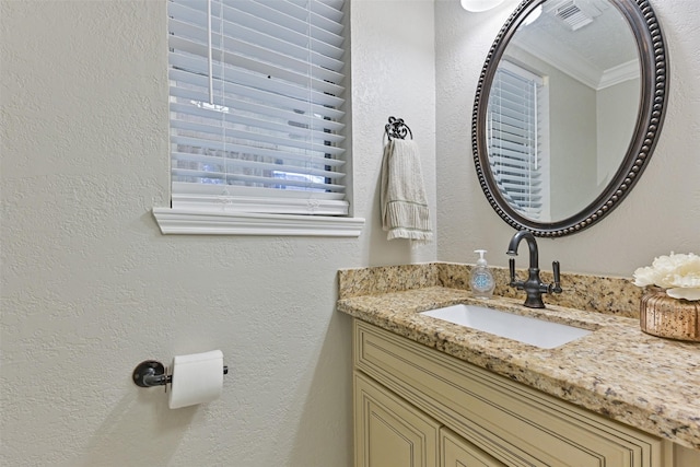 bathroom featuring vanity, crown molding, a textured wall, and visible vents