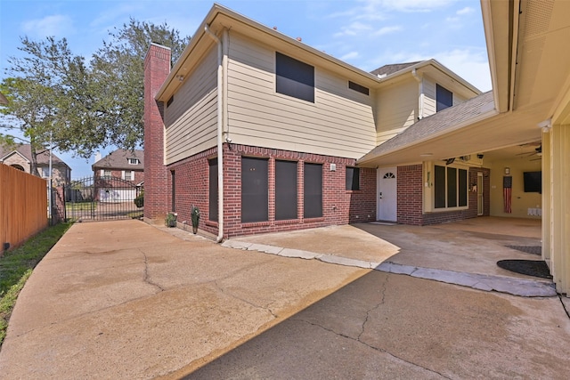 exterior space with a gate, fence, a chimney, a patio area, and brick siding