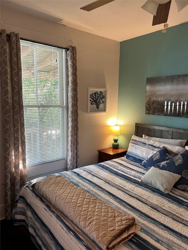 bedroom featuring a ceiling fan and a textured wall