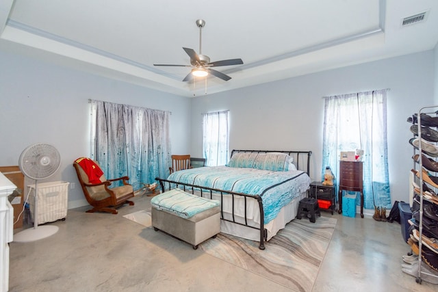 bedroom featuring concrete floors, a tray ceiling, multiple windows, and visible vents