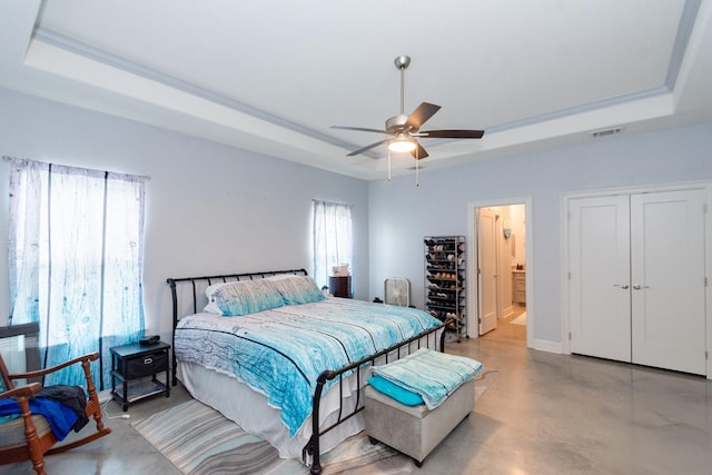 bedroom with finished concrete flooring, visible vents, baseboards, ceiling fan, and a tray ceiling