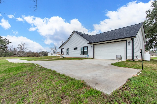 view of property exterior featuring a garage, concrete driveway, a yard, and a shingled roof