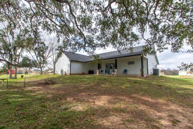 rear view of property with central AC and a yard