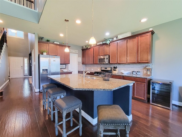 1904 Emerald Breeze Ct, Pearland, TX 77089 - kitchen featuring a breakfast bar, light stone counters, dark wood-type flooring, appliances with stainless steel finishes, and beverage cooler