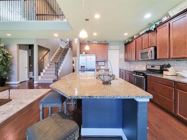 1904 Emerald Breeze Ct, Pearland, TX 77089 - kitchen featuring light stone countertops, dark wood-type flooring, tasteful backsplash, stainless steel appliances, and a breakfast bar area
