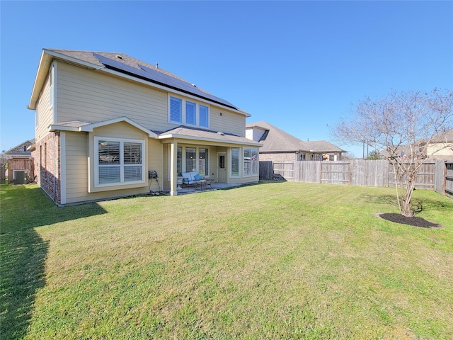 1904 Emerald Breeze Ct, Pearland, TX 77089 - rear view of house featuring roof mounted solar panels, a yard, a fenced backyard, cooling unit, and a patio