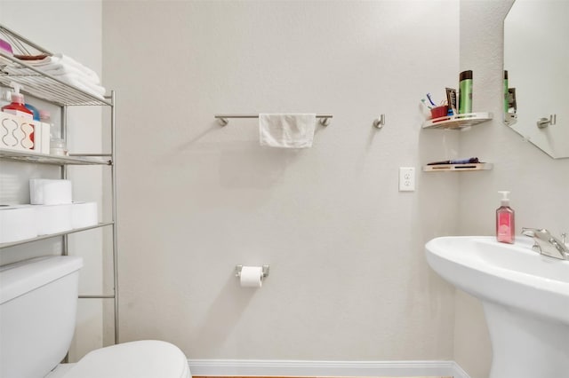 bathroom with toilet, baseboards, and a sink