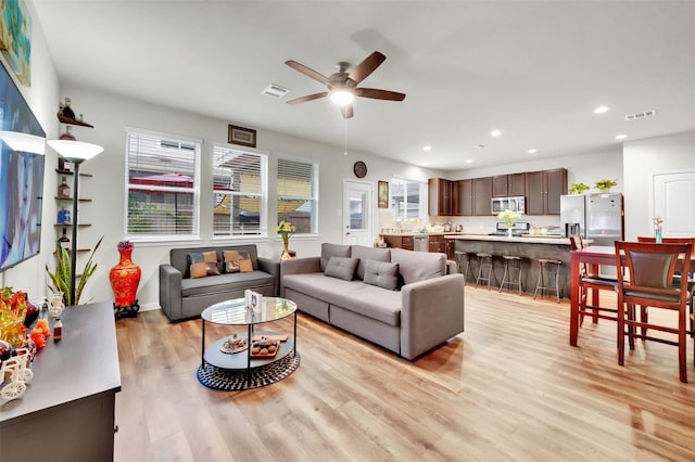 living room featuring light wood finished floors, a ceiling fan, visible vents, and recessed lighting