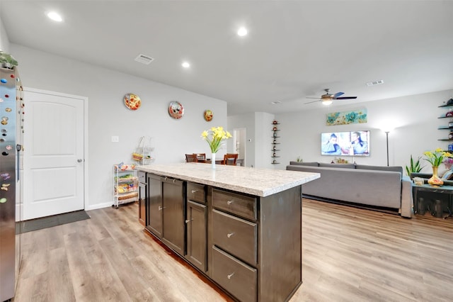 kitchen featuring light wood-style floors, visible vents, open floor plan, and a center island