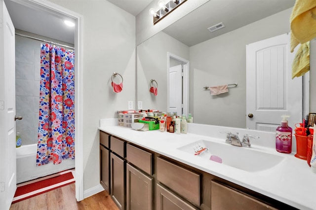 full bathroom featuring visible vents, shower / bath combo with shower curtain, wood finished floors, and vanity