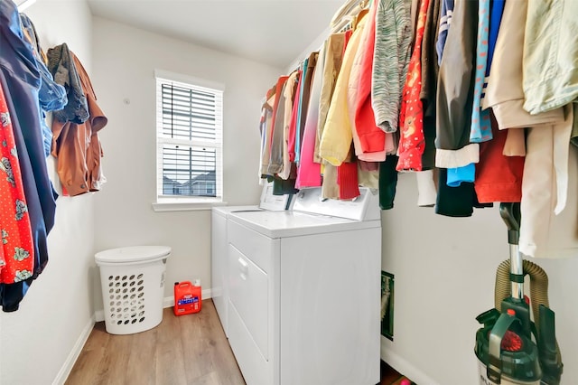 clothes washing area with laundry area, baseboards, light wood-style floors, and washing machine and clothes dryer