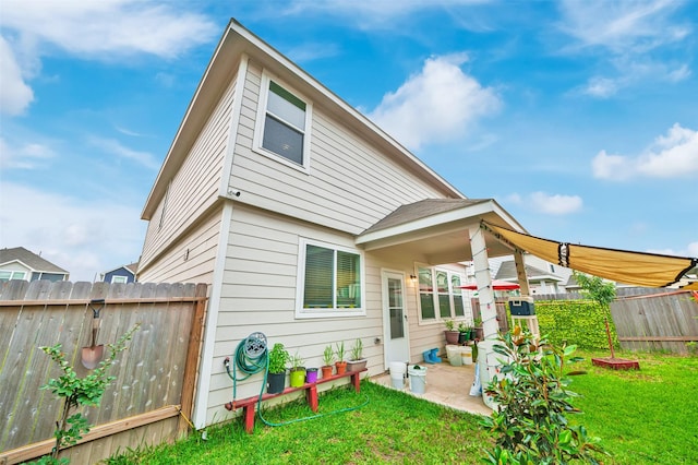 back of house with a patio area, fence, and a lawn