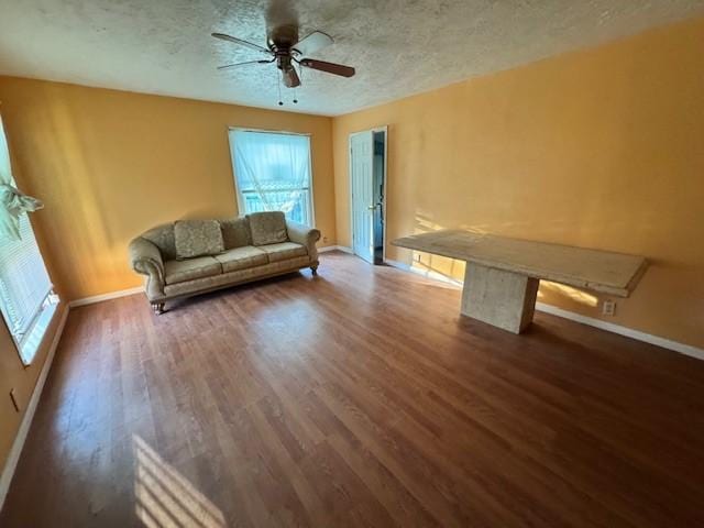 unfurnished living room with baseboards, a textured ceiling, ceiling fan, and wood finished floors